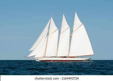 Side view of three-masted authentic windjammer or schooner passing by on a summer day with blue sky. Windjamming is a popular attraction in New England for the tourism industry.
