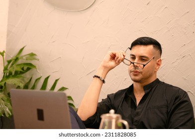 Side view of a tired and worried young man working in his home office and thinking of ideas while looking at his notebook screen.  - Shutterstock ID 2311828085