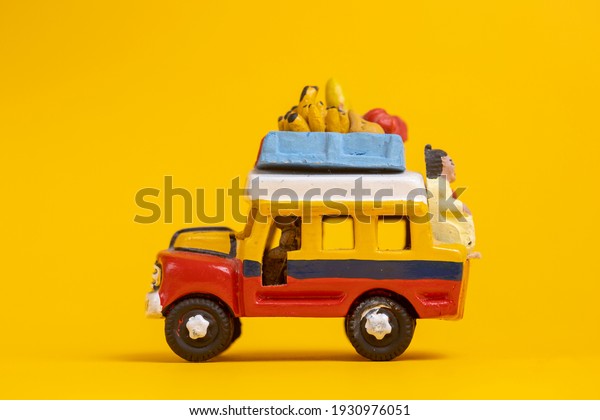 Side view of toy car vehicle with\
passenger on the back of colorful Colombia themed bus. Studio still\
life toy against a seamless yellow\
background