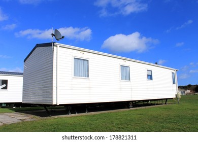 Side view of trailer on caravan park with blue sky and cloudscape background.