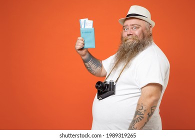 Side View Traveler Tourist Fat Obesy Man In White T-shirt Hat With Camera Hold Passport Tickets Isolated On Orange Background. Passenger Travel Abroad Weekends On Getaway. Air Flight Journey Concept
