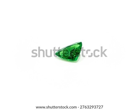 Side view of a triangular-cut tsavorite (green garnet) loose stone on a white background