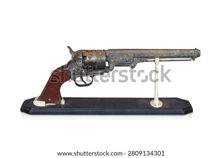 side view two antique and old brass guns with a brown leather grip, placed on a wooden stand against a white background