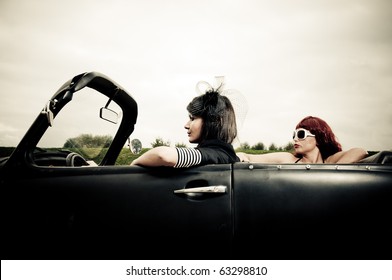 Side View Of Two Attractive Girls Driving Around In Vintage Car