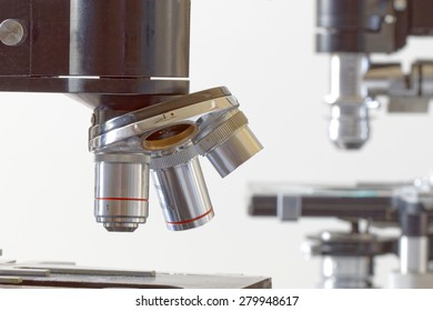 Side view of two black vintage microscopes, one in focus and one de-focused in the background