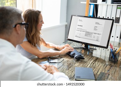 Side View Of Two Businesspeople Checking Invoice On Computer Over Desk At Workplace - Shutterstock ID 1492520300