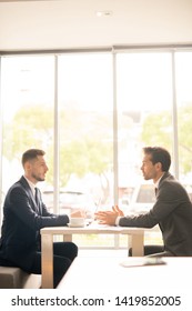 Side view of two confident employees in formalwear negotiating about terms of contract at meeting in cafe or restaurant - Shutterstock ID 1419852005