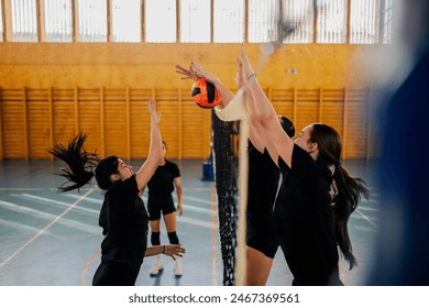 Side view of a two female volleyball teams in action at the net while playing a match in a sports hall. Group of diverse woman blocking a ball during a competition. Copy space. - Powered by Shutterstock