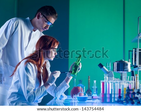 side view of two forensics scientists taking fingerprints from bottle, in a laboratory