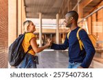 Side view of two happy multi-ethnic students shaking hands at the university