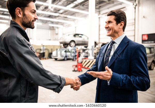 Side view of
two men standing at an auto
workshop