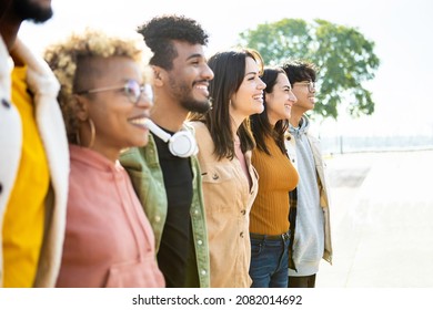 Side View Of United Multiracial People Hugging Each Other In Cooperation - Group Of Happy Young Friends Supporting Together In Line - Cooperation, Teamwork And Unity Concept