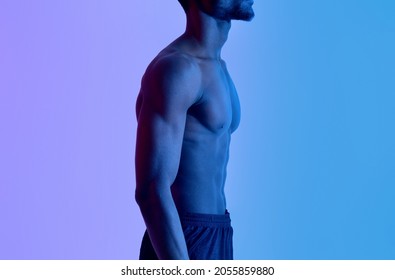 Side View Of Unrecognizable Young Black Sportsman With Muscular Bare Torso Posing In Neon Lighting. Sexy African American Man Demonstrating His Strong Body, Closeup