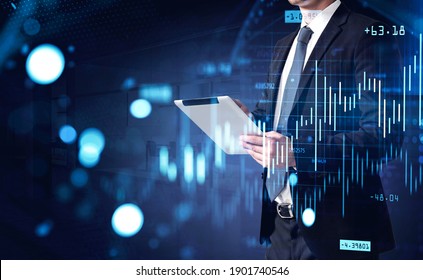 Side view of an unrecognizable young businessman using tablet computer in blurry office with double exposure of graphs. Toned image