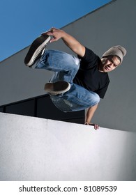 Side View Of Urban Parkour Free Runner Jumping Over A Wall