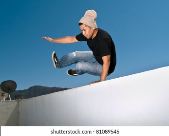 side view of urban parkour free runner jumping over a wall - Powered by Shutterstock