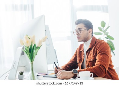 Side view of ux designer working with computer and graphics tablet on table in office - Shutterstock ID 1677149713