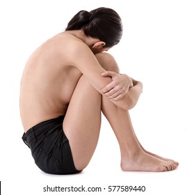 Side View Of Very Thin Girl Sitting With Her Arms Wrapped About Her Knees, Isolated On White