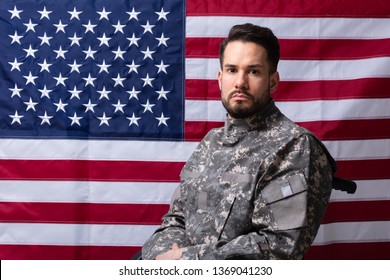 Side View Of Veteran Sitting In Wheelchair In Front Of An American Flag