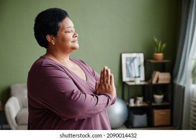 Side View Waist Up Portrait Of Black Senior Woman Meditating At Home With Eyes Closed