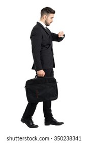 Side View Of Walking Businessman Checking Hand Watch Time. Full Body Length Portrait Isolated Over White Studio Background.