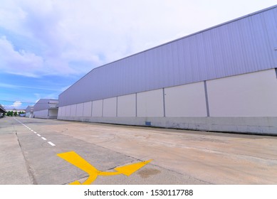 Side View Of A Warehouse With Yellow Arrow Sign On The Ground.