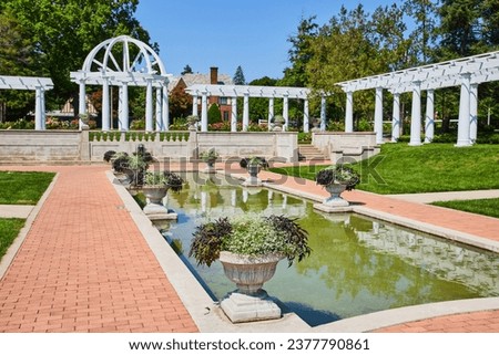 Side view of water pool along stone path leading to gorgeous outdoor wedding spot with pergola