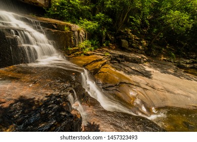 Side view of waterfall cascading down the side of mountain into basin below.