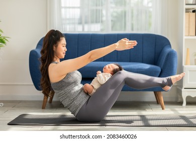 Side View Of Wellness Asian Woman Mom Doing Yoga Boat Pose Or Navasana With Baby At Cozy Home.Happy Healthy Mother Yoga Exercise Newborn Baby Boy Sleep And Lying On Leg Mom.Yoga Mom And Baby Concept