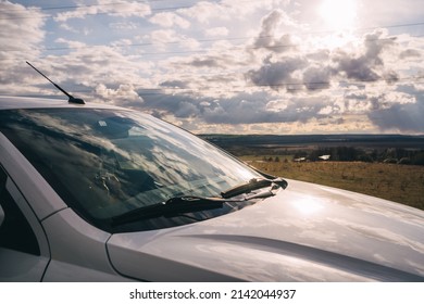 side view of a white car on the background of nature at sunset. landscape and tourism concept. horizontal banner of a car with a view to the horizon.reflection on the windshield of the car - Shutterstock ID 2142044937