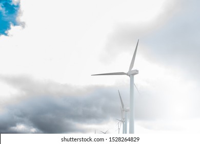 side view of wind turbines between clouds in the sky