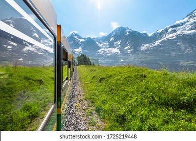 Side View From Window Of Modern Electric Green And Yellow Tourist Train Of The Wengernalpbahn Rack Railway From Lauterbrunnen To Kleine Scheidegg Near Kleine Scheidegg Railway, Switzerland