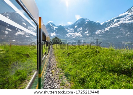 Side view from window of modern electric green and yellow tourist train of the Wengernalpbahn rack railway from Lauterbrunnen to Kleine Scheidegg near Kleine Scheidegg railway, Switzerland