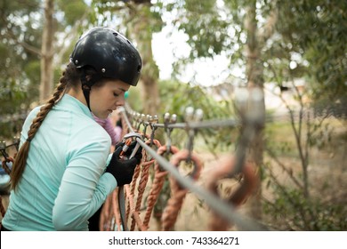 Side View Of Woman Attaching Carabiner To Rope Bridge