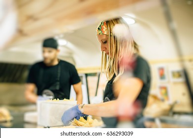 Side view of woman chef preparing nachos in mexican food truck.