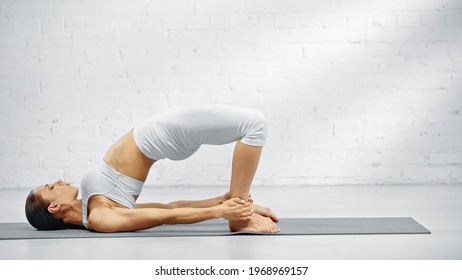 Side View Of Woman Doing Bridge Pose On Yoga Mat