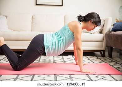 Side View Of Woman Doing Press-ups During Her Pregnancy On Exercise Mat At Home