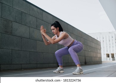 Side view of woman doing squats outdoors - Shutterstock ID 1813224736