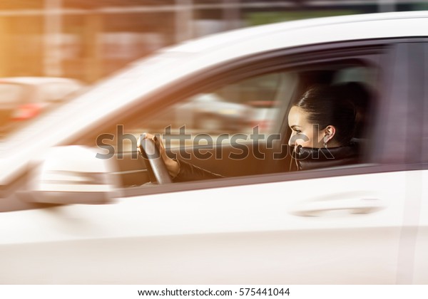 Side view of a woman driving a\
car. Woman driving fast. Beautiful woman speeding in a\
automobile.