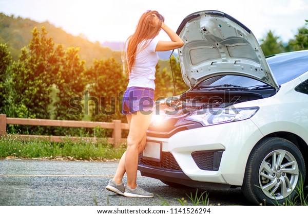 Side view of woman gets some problem or trouble\
because her car can not run or can not start, she opened the hood\
Broken car on the side See engines that are damaged or\
not.,accident concept