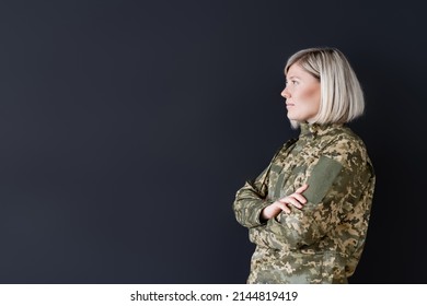 Side View Of Woman In Military Uniform Standing With Crossed Arms Isolated On Black