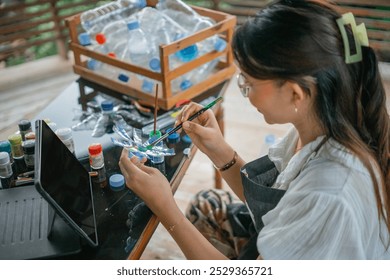 side view of woman painting recycled plastic bottle handcraft - Powered by Shutterstock