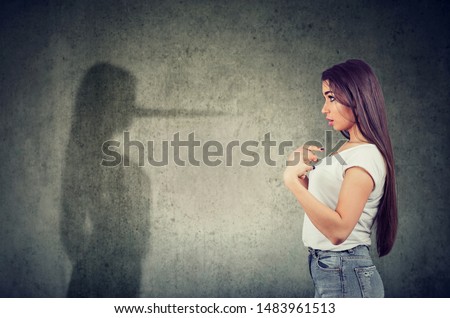 Side view of a woman pointing at herself looking at a shadow with long nose of a liar.