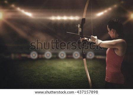 Side view of woman practicing archery on a sports field