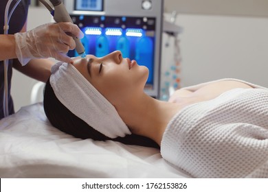 Side View Of Woman Receiving Microdermabrasion Therapy On Forehead At Beauty Spa