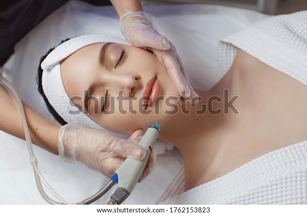 Side view of woman receiving microdermabrasion\
therapy on forehead at beauty\
spa