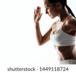 Side view of woman in sportswear working out against white background. Female athlete exercising in studio.