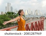 Side view of woman traveling in Cartagena de Indias. Horizontal view of latin woman sightseeing with Bocagrande skyline in the background. Travel to Colombia concept.