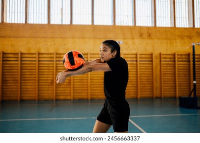 Side view of a woman using bump pass while playing volleyball match or training in a sports hall. Woman volleyball athlete in action participating in an indoor volleyball competition. Copy space. - Powered by Shutterstock