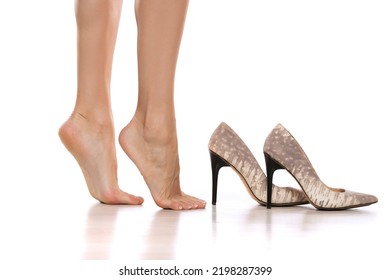 Side view of a woman's bare feet and high heels on a white studio background.